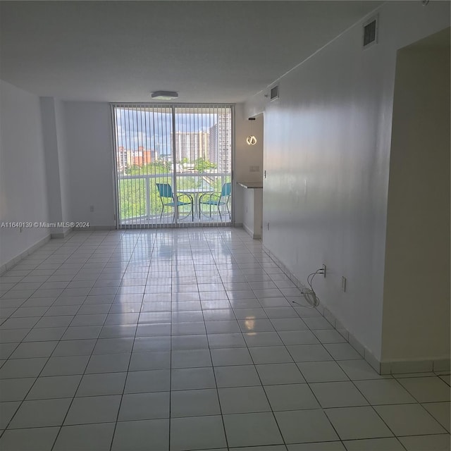 tiled spare room featuring a wall of windows