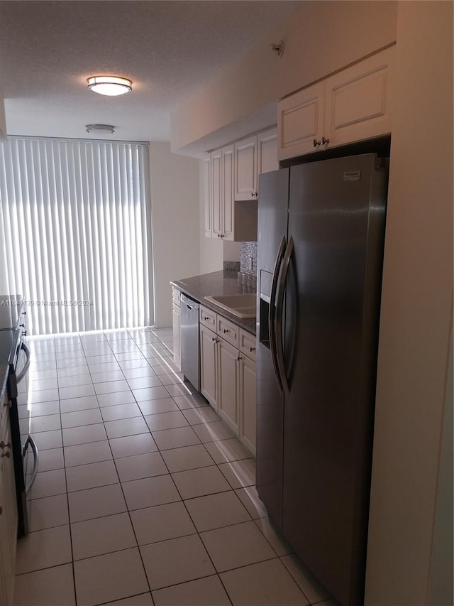 kitchen with white cabinetry, a textured ceiling, light tile patterned floors, sink, and appliances with stainless steel finishes