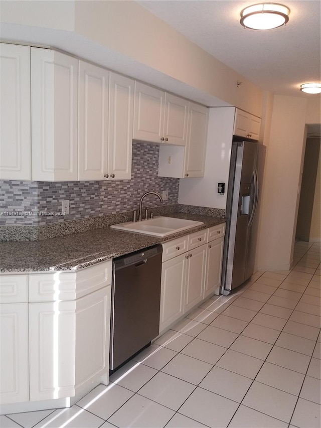 kitchen featuring dark stone counters, backsplash, sink, appliances with stainless steel finishes, and white cabinets