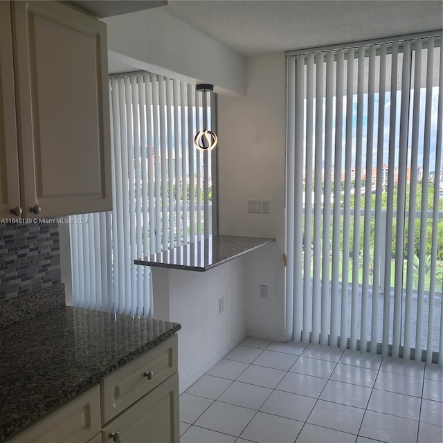 kitchen with dark stone countertops, kitchen peninsula, and light tile patterned flooring