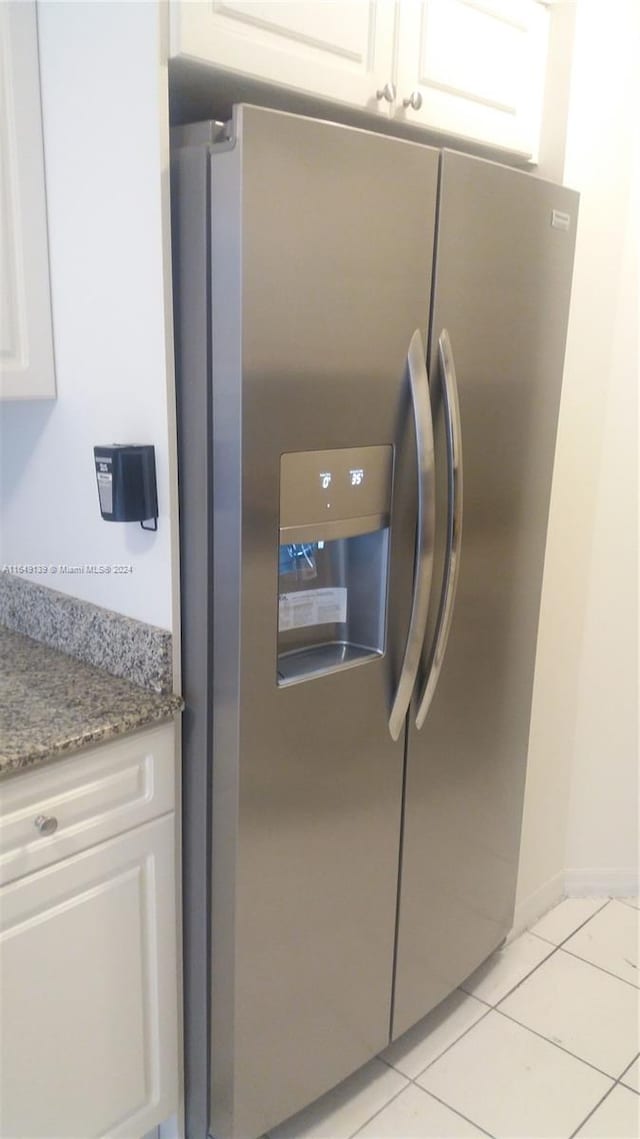 details featuring white cabinets, light tile patterned floors, stainless steel fridge with ice dispenser, and stone countertops