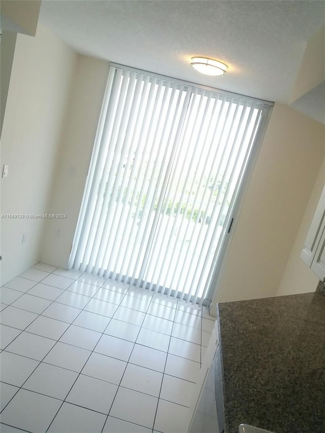 empty room with a textured ceiling, a healthy amount of sunlight, and light tile patterned floors