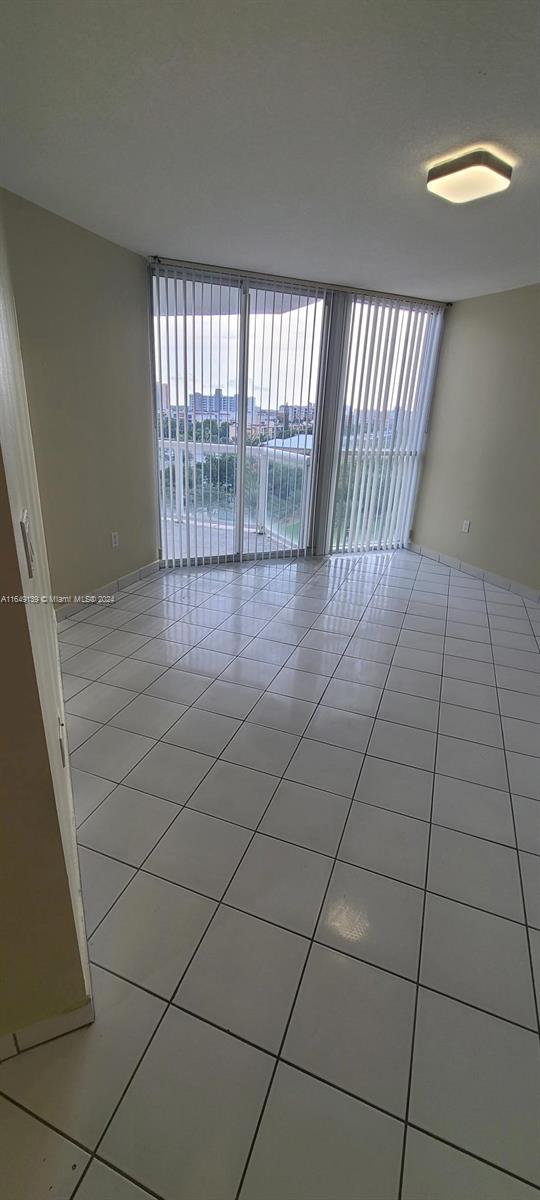 tiled empty room featuring a wall of windows