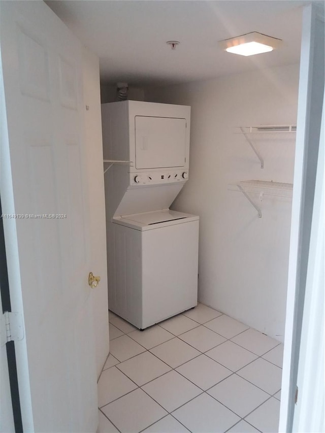 laundry area with light tile patterned floors and stacked washer and dryer