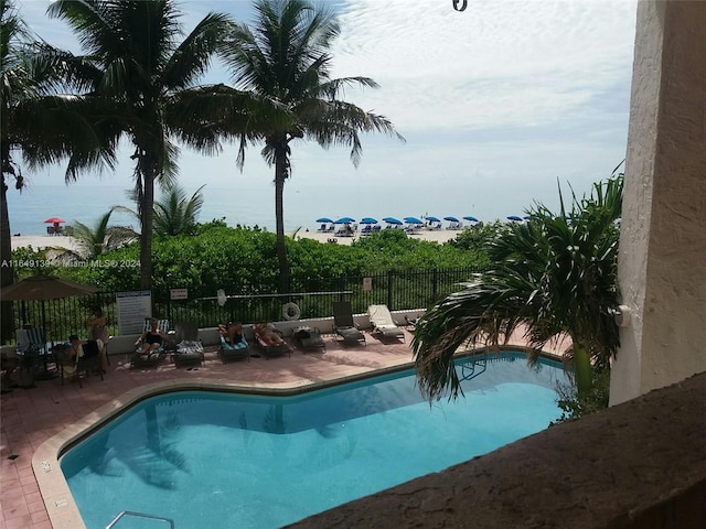 view of swimming pool featuring a water view and a patio