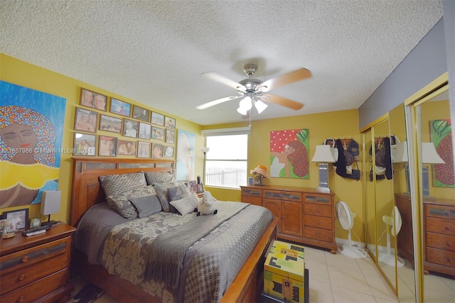 bedroom featuring a closet, ceiling fan, light tile patterned flooring, and a textured ceiling