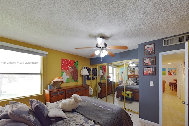 tiled bedroom with a textured ceiling, ceiling fan, and multiple windows