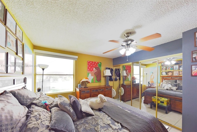 bedroom featuring multiple windows, ceiling fan, light tile patterned floors, and a textured ceiling