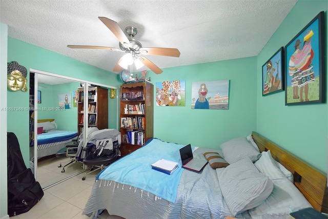 tiled bedroom with a textured ceiling, ceiling fan, and a closet