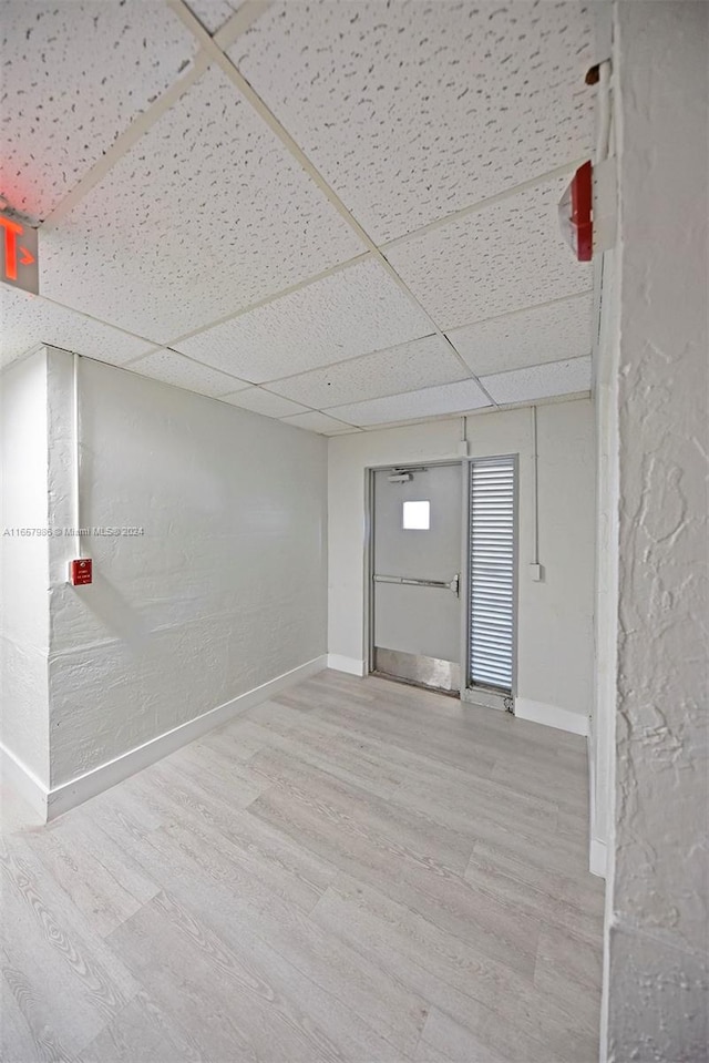 basement with light hardwood / wood-style flooring and a drop ceiling