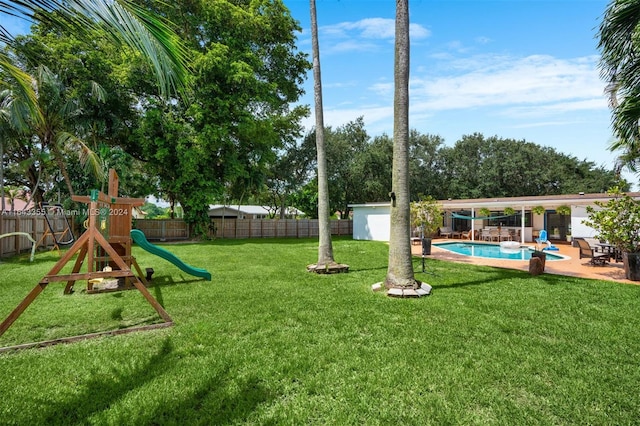 view of yard featuring a playground, a fenced in pool, a storage unit, and a patio area