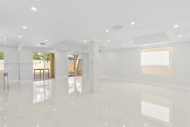 empty room featuring a tray ceiling and ornate columns