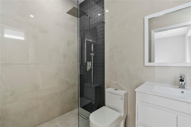 bathroom featuring vanity, toilet, tile walls, and a tile shower