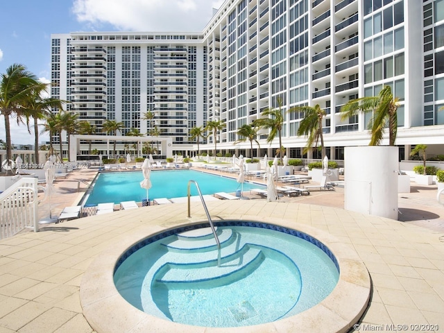 view of swimming pool featuring a community hot tub and a patio