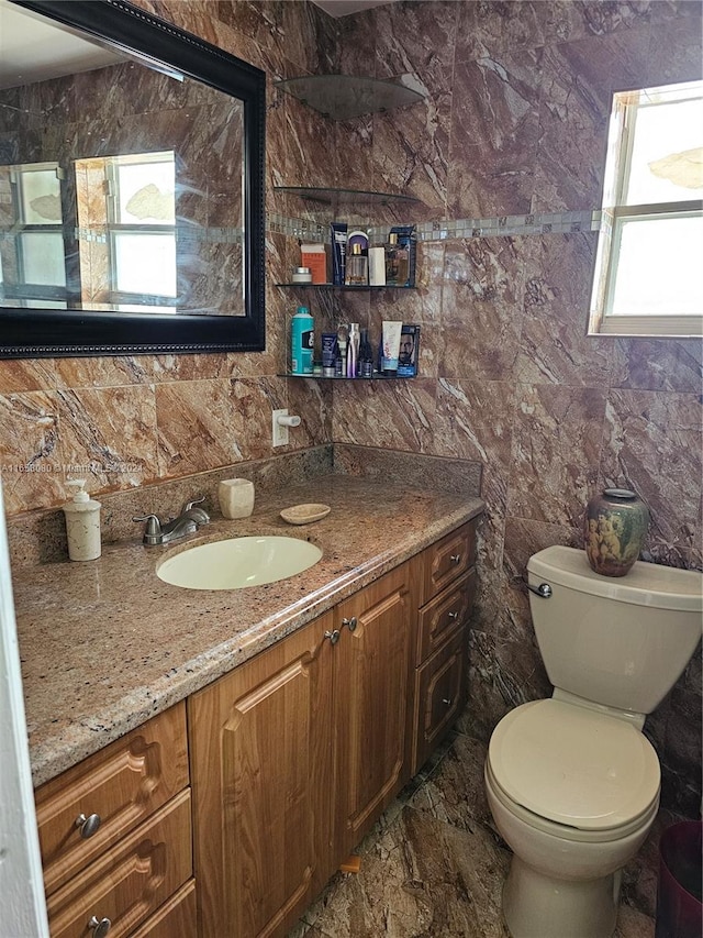 bathroom featuring vanity, toilet, plenty of natural light, and tile walls