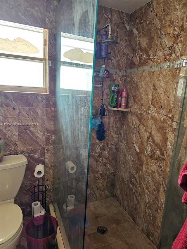 bathroom with tile walls, toilet, and a tile shower