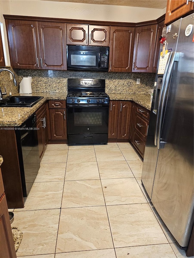 kitchen featuring black appliances, sink, light stone countertops, and backsplash