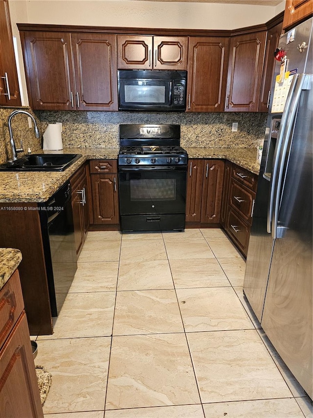 kitchen featuring black appliances, light stone counters, sink, and tasteful backsplash