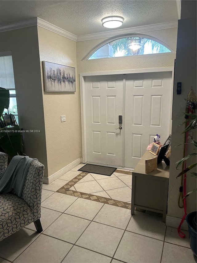 tiled foyer entrance with ornamental molding and a textured ceiling