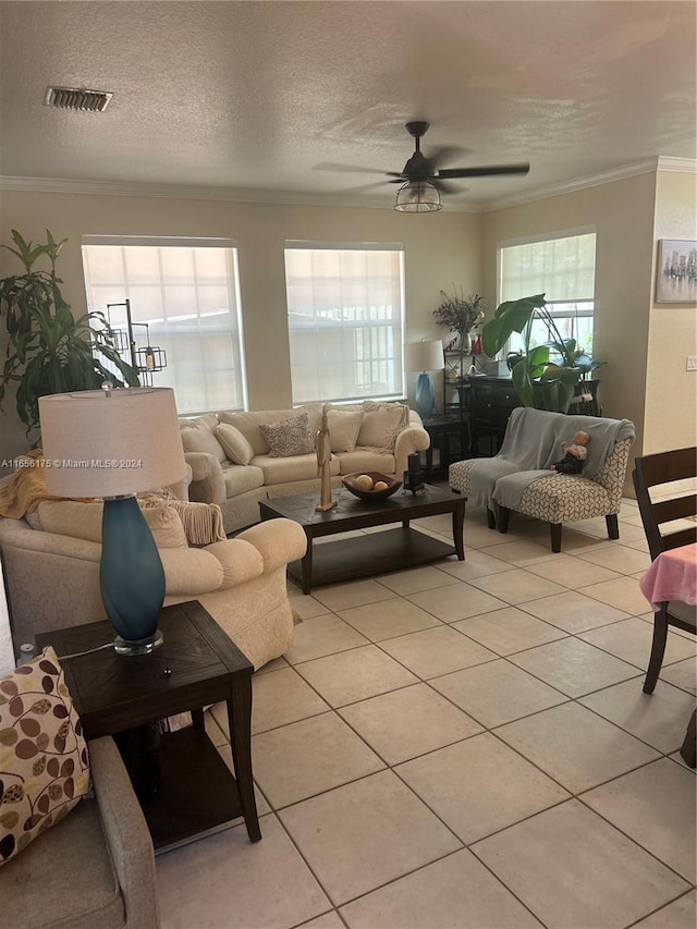 living room with ornamental molding, ceiling fan, light tile patterned floors, and a textured ceiling