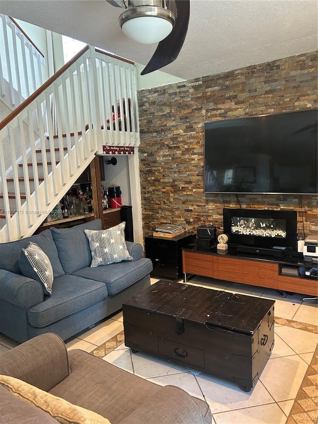 living room with a textured ceiling, a fireplace, and light tile patterned floors