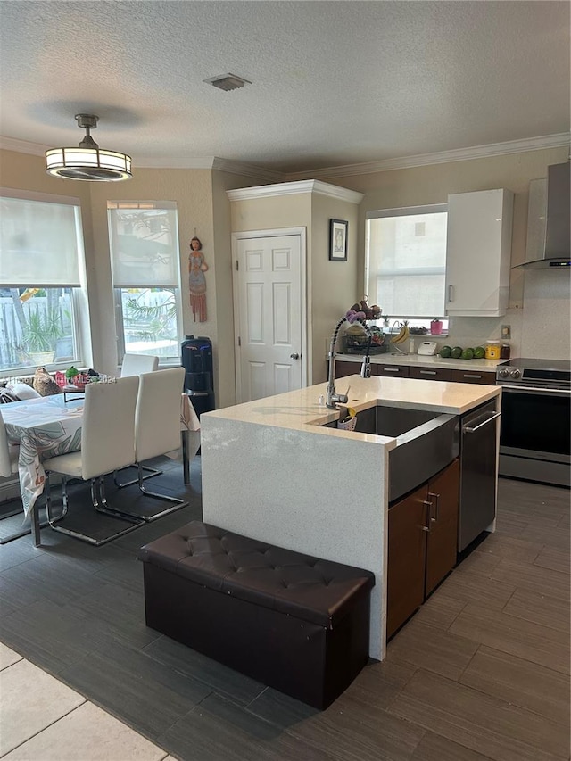 kitchen with appliances with stainless steel finishes, plenty of natural light, hardwood / wood-style floors, and wall chimney range hood