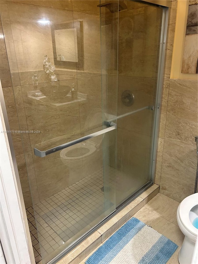 bathroom with toilet, an enclosed shower, and tile patterned floors