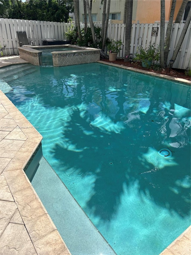 view of swimming pool with an in ground hot tub