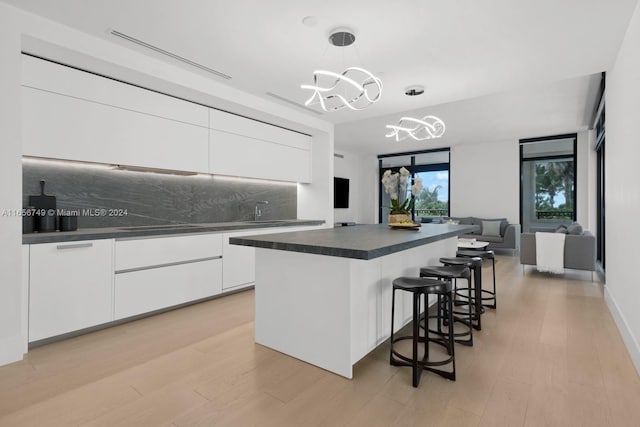 kitchen featuring pendant lighting, a center island, light hardwood / wood-style floors, and white cabinets