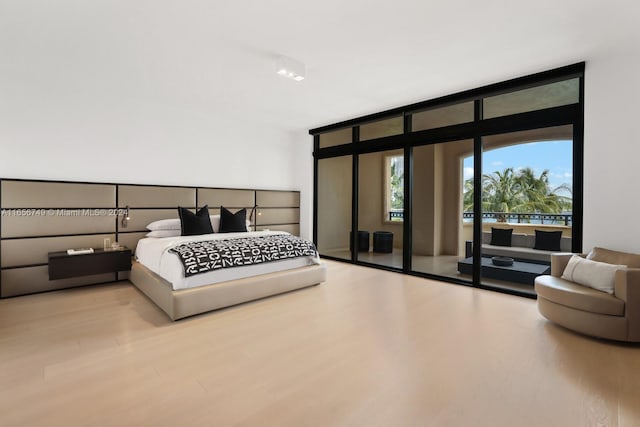 bedroom featuring a wall of windows and light wood-type flooring