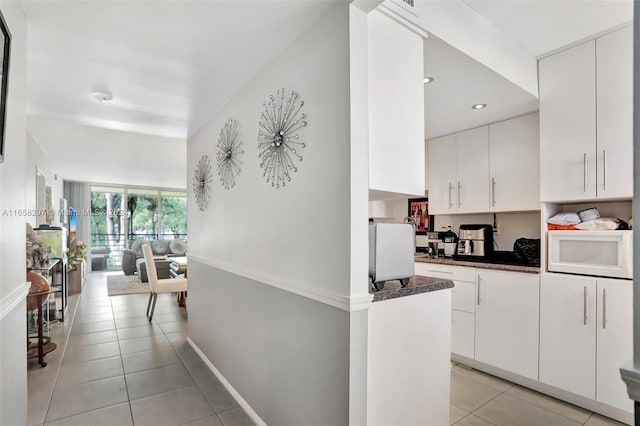 kitchen with white cabinets, light tile patterned floors, and white microwave