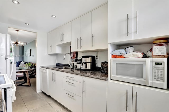 kitchen with white appliances, sink, a chandelier, dark stone countertops, and white cabinets