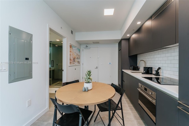 kitchen featuring light tile patterned floors, backsplash, electric panel, black electric cooktop, and stainless steel oven