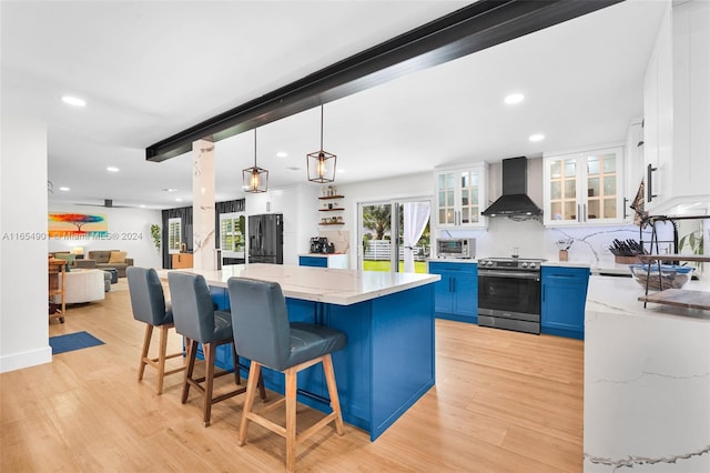 kitchen with stainless steel electric range, a center island, blue cabinetry, white cabinetry, and wall chimney exhaust hood