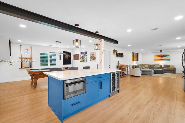 kitchen featuring pool table, hanging light fixtures, light wood-type flooring, stainless steel oven, and blue cabinets