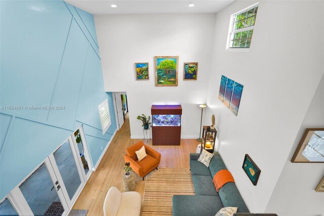 living room with light wood-type flooring and a towering ceiling