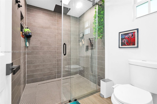 bathroom with toilet, wood-type flooring, and an enclosed shower