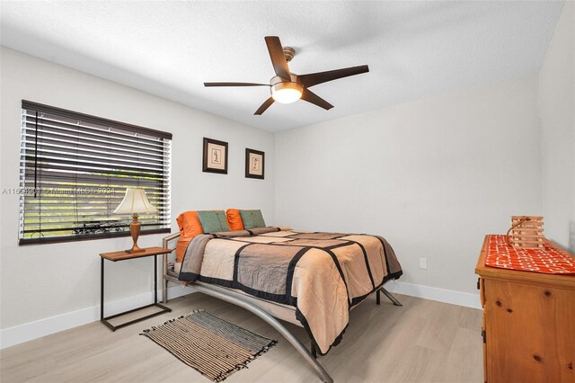 bedroom with a textured ceiling, ceiling fan, and light hardwood / wood-style floors