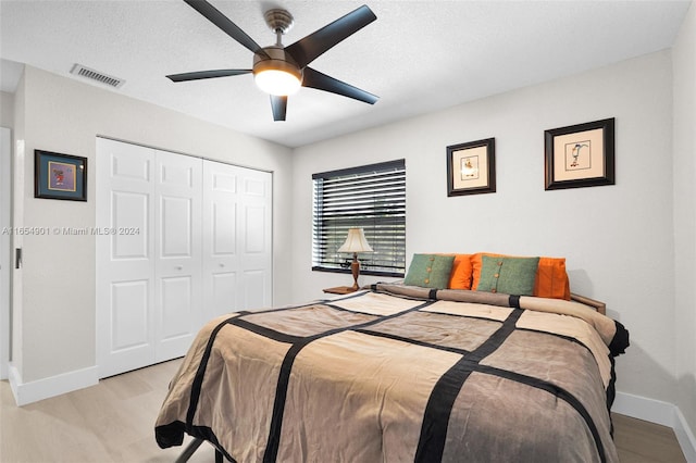 bedroom with a closet, ceiling fan, a textured ceiling, and light hardwood / wood-style flooring