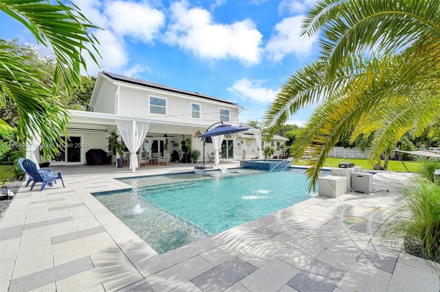 view of pool featuring pool water feature, ceiling fan, and a patio