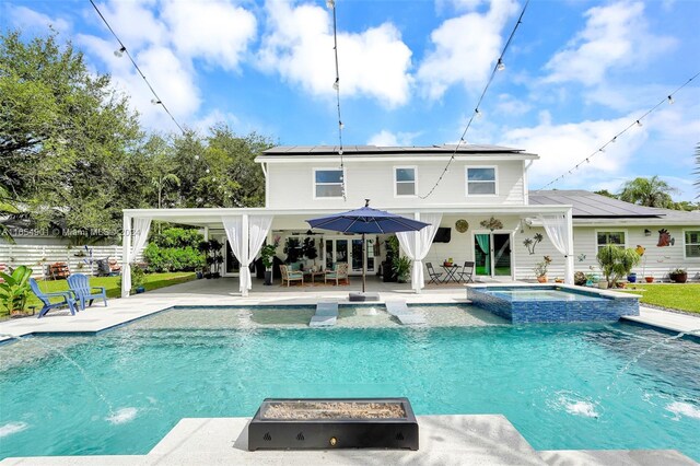 view of swimming pool with pool water feature, a patio area, and an in ground hot tub