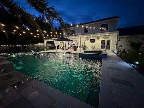 pool at twilight featuring a gazebo