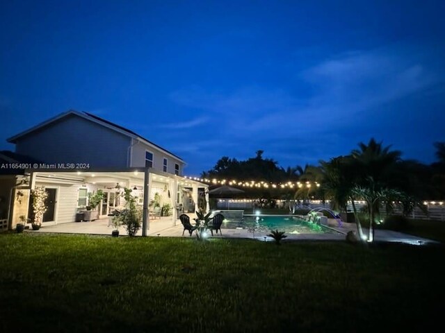 pool at twilight featuring a lawn and a patio