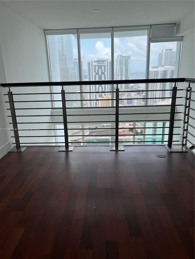 corridor with floor to ceiling windows, wood-type flooring, and a healthy amount of sunlight