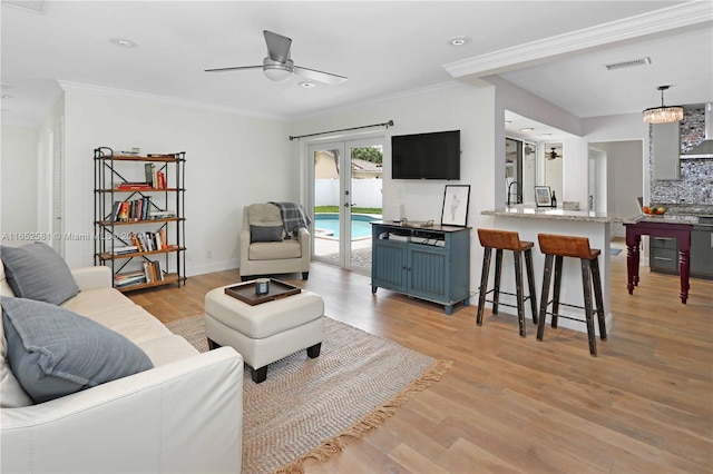 living room featuring french doors, ceiling fan, ornamental molding, and light hardwood / wood-style flooring