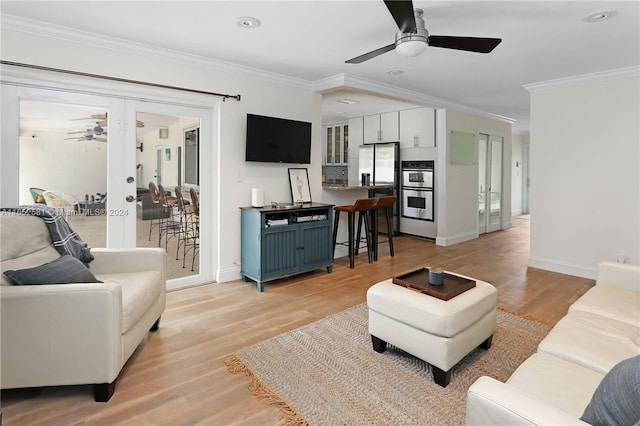 living room with crown molding, light wood-type flooring, and ceiling fan