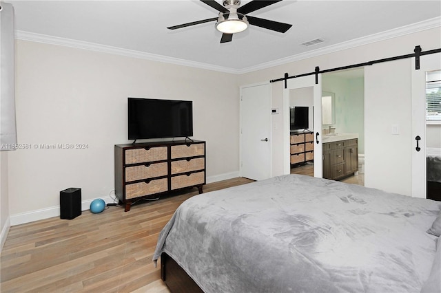 bedroom with a barn door, ceiling fan, light hardwood / wood-style floors, connected bathroom, and ornamental molding