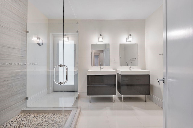 bathroom with tile patterned floors, two vanities, a stall shower, a sink, and baseboards