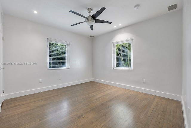 empty room with hardwood / wood-style floors, baseboards, and visible vents