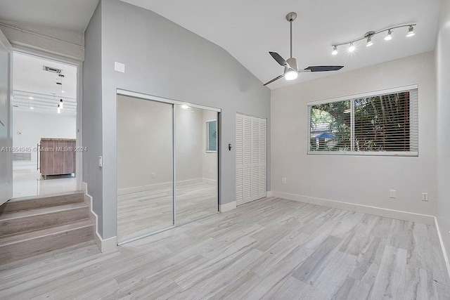 unfurnished bedroom featuring wood finished floors, visible vents, baseboards, high vaulted ceiling, and two closets